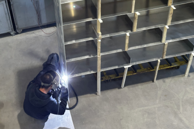 Soudure en atelier pour la fabrication d’une bibliothèque en alu sur mesure, phase de l’assemblage des étagères.