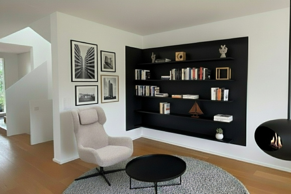 Montage IA d’un salon contemporain avec bibliothèque noire réalisée sur mesure, fauteuil design, tables basses et cheminée suspendue.