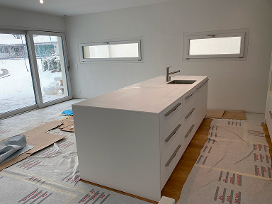 Îlot central de cuisine en cours d’installation avec plan de travail blanc, évier intégré et rangements