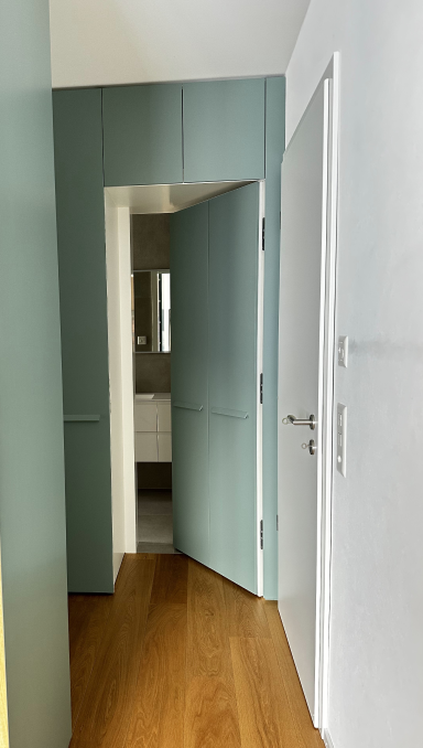 Dressing sur mesure vert sauge avec porte intégrée menant à la salle de bain, vue depuis le couloir